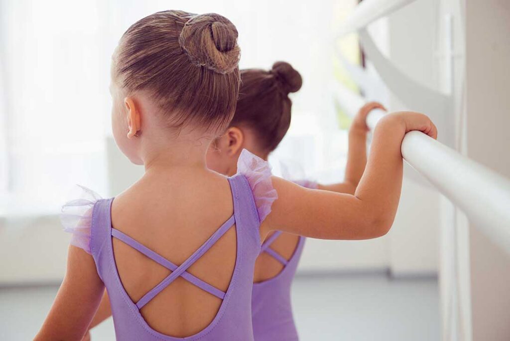 Adults practice coordinated dance steps in a bright studio while following music and movement cues.