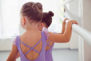 Adults practice coordinated dance steps in a bright studio while following music and movement cues.