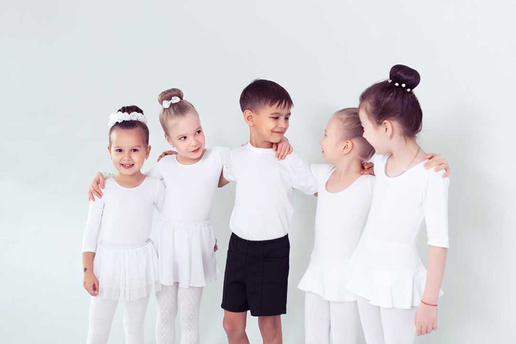Parent watching a young dancer practice footwork in a bright studio with dance shoes nearby